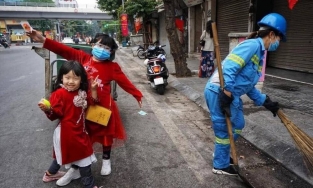 2 em bé xúng xính áo dài đỏ theo mẹ lao công đi quét rác chiều mùng Một Tết