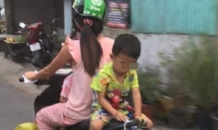 Người mẹ chở con nhỏ đi xe máy, để con ngồi ngược sau yên xe vô tư chơi đùa