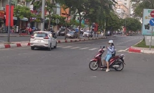 Cô gái dừng xe máy giữa đường đứng bấm điện thoại như 'đường này là của em'