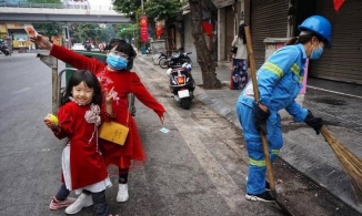 2 em bé xúng xính áo dài đỏ theo mẹ lao công đi quét rác chiều mùng Một Tết