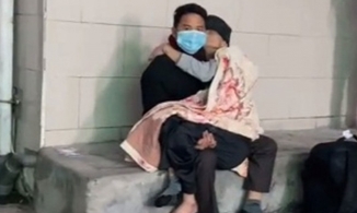 Người con trai bế mẹ già trong lòng chờ khám bệnh