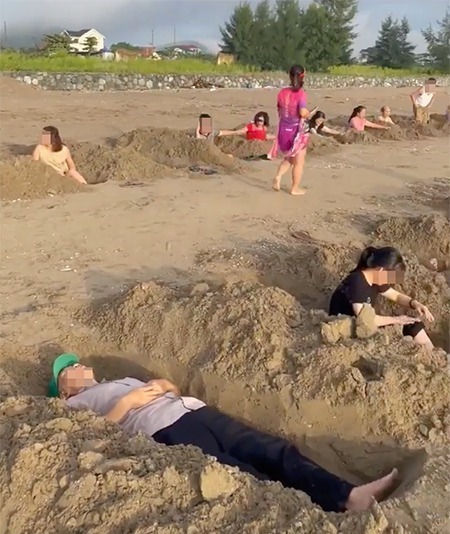 Nhóm người đào hố cát để nằm