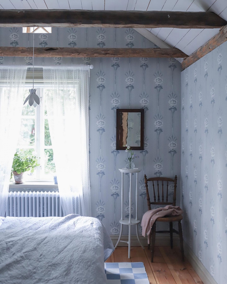 Bức tường phòng ngủ được tô điểm bằng giấy dán tường mới, hình ảnh những bông hoa trắng trang nhã nên nền màu xanh lam dịu nhẹ. 