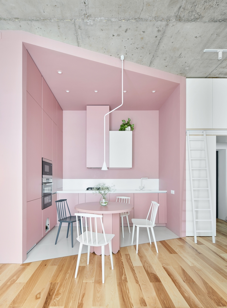 Phòng bếp và khu vực ăn uống thiết kế mở với phòng khách nhưng vẫn tạo được sự phân vùng mạnh mẽ nhờ sắc hồng ngọt ngào cùng sàn gạch trắng tương phản với sàn gỗ ấm áp.