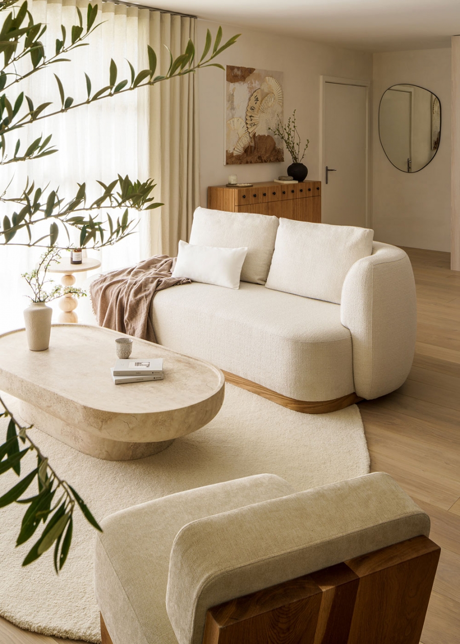 Phòng khách thiết mở với nội thất toát lên sự êm ái và mềm mại, từ chiếc ghế sofa cong cong, thảm trải sàn cho đến chiếc bàn nước hình oval.