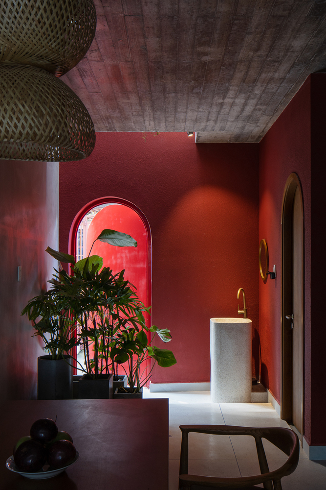 Phía cuối tầng trệt bố trí bồn rửa tay bằng đá với vòi rửa mạ vàng đồng sang chảnh, kết hợp những chậu cây cảnh tươi xanh nổi bật trên phông nền màu đỏ mận.