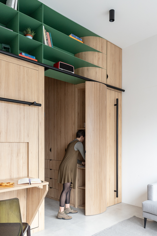 Cạnh phòng khách là hệ thống tủ kệ lưu trữ nhiều ngăn được 'giấu nhẹm' đằng sau cánh cửa gỗ thiết kế bo tròn uyển chuyển.