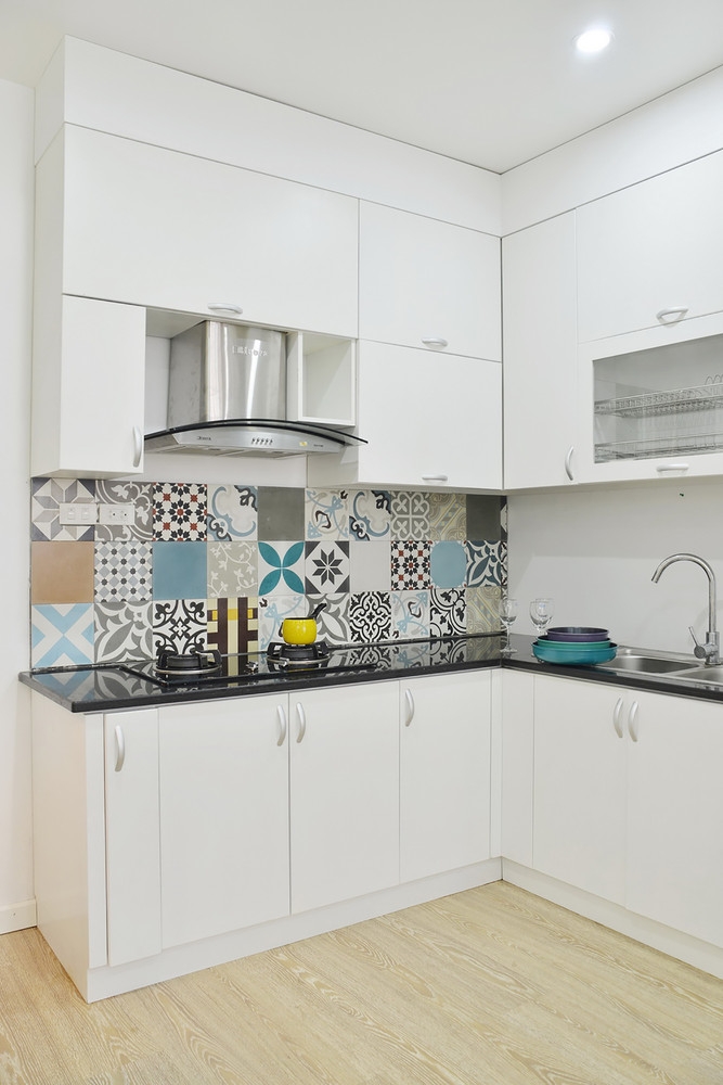 Phòng bếp thiết kế chữ L vừa nhỏ gọn vừa phù hợp với cấu trúc căn hộ. Việc sử dụng tone màu trắng giúp bếp sạch sẽ, sáng sủa hơn, đồng thời cũng có điểm nhấn từ gạch bông ốp backsplash.