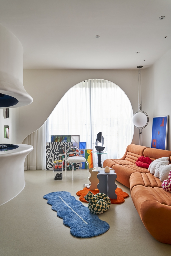 Phòng khách với bộ ghế sofa gam màu cam ấm áp, bàn nước, thảm trải sàn và tranh ảnh trang trí đều đa dạng về kiểu dáng lẫn màu sắc.