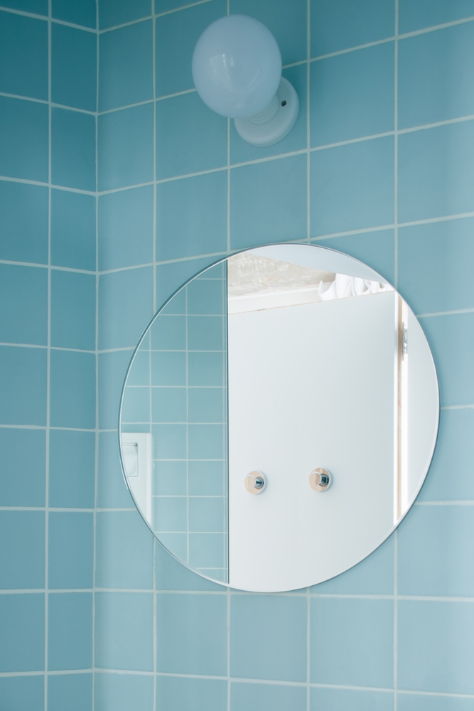 Không chỉ bên ngoài phòng tắm mà cả khu vực bên trong, NTK cũng không bỏ qua phụ kiện gương soi. Tấm gương tròn trang trí trên tường vừa để soi (dĩ nhiên rồi!), tạo chiều sâu vừa giúp 'cơi nới' căn phòng bằng thị giác.