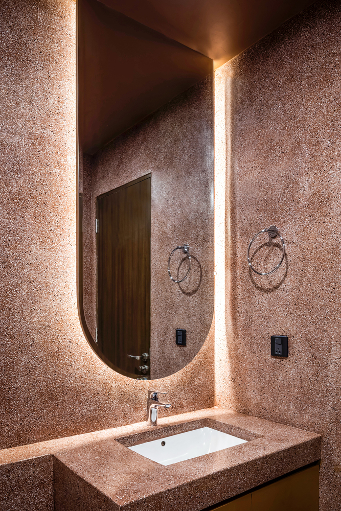 Khu vực phòng tắm được ốp lát bằng gạch họa tiết terrazzo màu hồng đất ấm áp. Tấm gương với thiết kế bo tròn mềm mại tạo sự kết nối về đường nét nội thất trong tổng thể căn hộ.