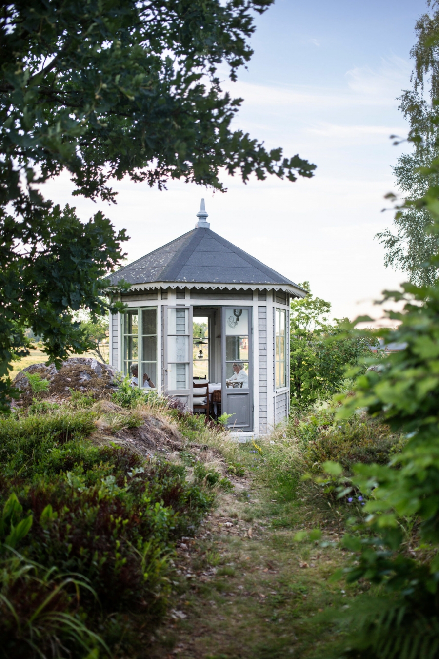 'Lâu đài mini' với tone xanh xám sang trọng trong ngôi nhà đồng quê của vợ chồng nghệ sĩ người Thụy Điển khiến người nhìn cảm giác như đang lạc vào một khu vườn cổ tích. Hình ảnh họ ngồi chuyện trò cùng nhau trông tĩnh tại và thư thái vô cùng.