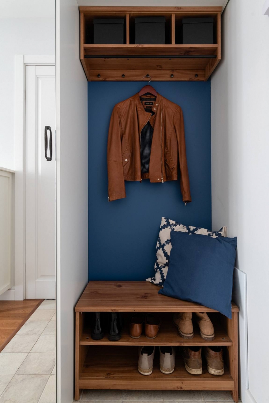 Lối vào căn hộ tận dụng hốc tường để bố trí kệ đựng giày dép, móc treo áo khoác, kệ lưu trữ trên cao và đặc biệt là gam màu xanh lam đã xuất hiện từ cái nhìn đầu tiên.