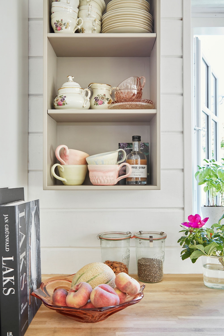 Kệ lưu trữ âm tường ở bếp được dùng làm nơi trưng bày bộ sưu tập ly tách, ấm trà,... trông xinh xắn vô cùng. Hoa văn của những dụng cụ này cũng rất hài hòa với nội thất.