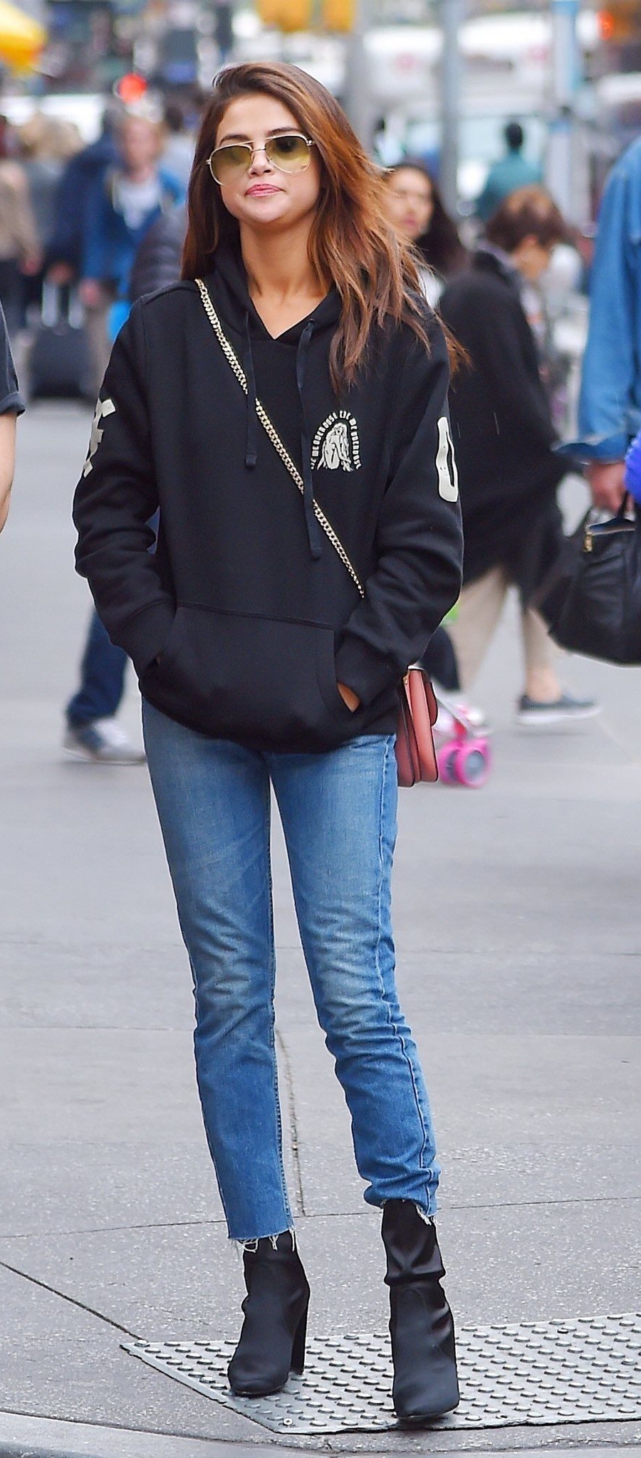 Selena mặc quần jeans xanh nhạt dáng cơ bản cùng áo hoodie đen bắt tông với boots - Ảnh: Internet