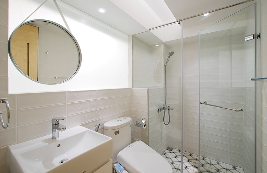 Hai phòng tắm trong căn hộ được sử dụng gạch ốp lát khác nhau nhằm tạo sự phong phú về mặt thị giác. Cửa kính trong suốt giúp phân vùng buồng tắm đứng và toilet mà không tạo cảm giác bí bách.