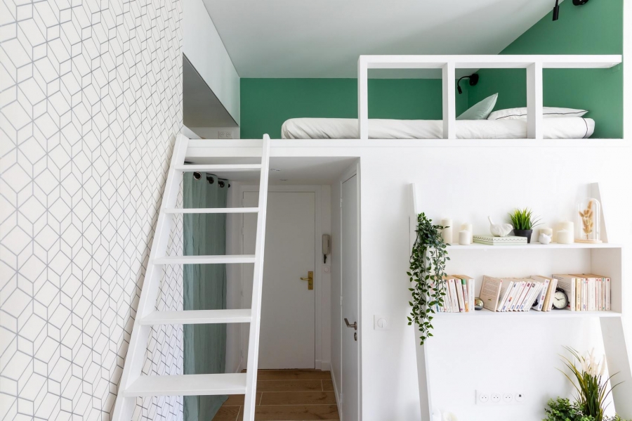 Một chiếc thang nhỏ màu trắng dẫn chúng ta lên phòng ngủ trên gác lửng. Vì căn hộ có ưu điểm trần cao 3,5m nên dễ dàng để thiết kế không gian nghỉ ngơi tương đối thoải mái với đệm dày dặn và đèn ngủ gắn tường đối xứng.