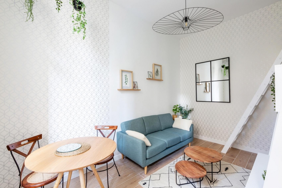 Phòng khách với bộ ghế sofa màu xanh lam, nổi bật trên nền tường trắng. Bộ bàn nước bằng gỗ hình tròn 1 kích thước đặc trưng của nội thất Scandinavian. 