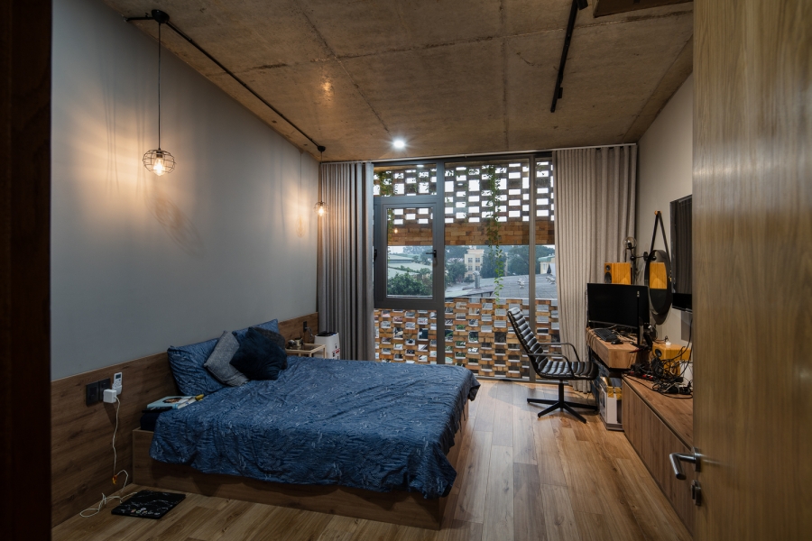 Phòng ngủ kết hợp góc làm việc tại gia với nội thất gỗ cùng cửa kính nhìn ra khung cảnh bên ngoài.