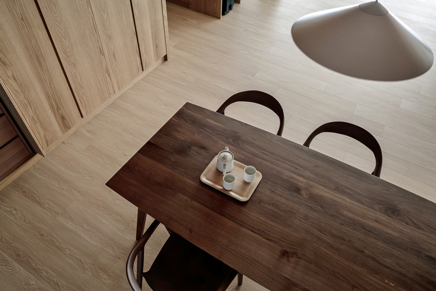 Bộ bàn ăn bằng gỗ với tone màu đậm hơn so với hệ thống tủ lưu trữ và sàn nhà để tạo điểm nhấn tương phản nhẹ nhàng.