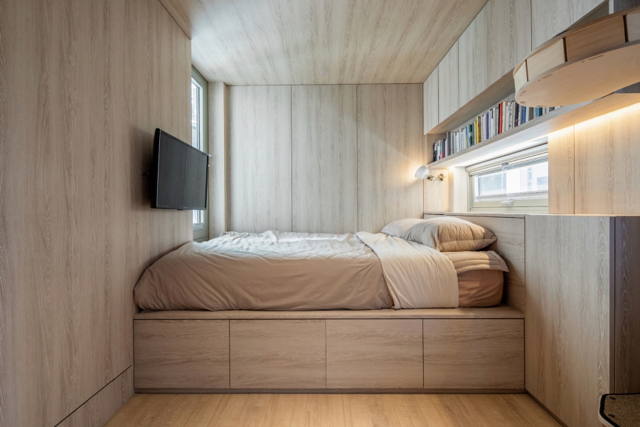 Phòng ngủ thiết kế tối giản nhưng vẫn tận dụng tối đa bề mặt tường và chiều cao trần để lắp đặt hệ thống tủ kệ lưu trữ gọn gàng. 