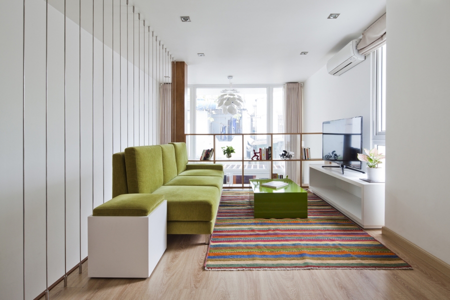 Phòng khách ở tầng lửng với đầy đủ nội thất như sofa, bàn nước, tủ tivi,... đặc biệt là tấm thảm trải sàn rực rỡ sắc cầu vồng!