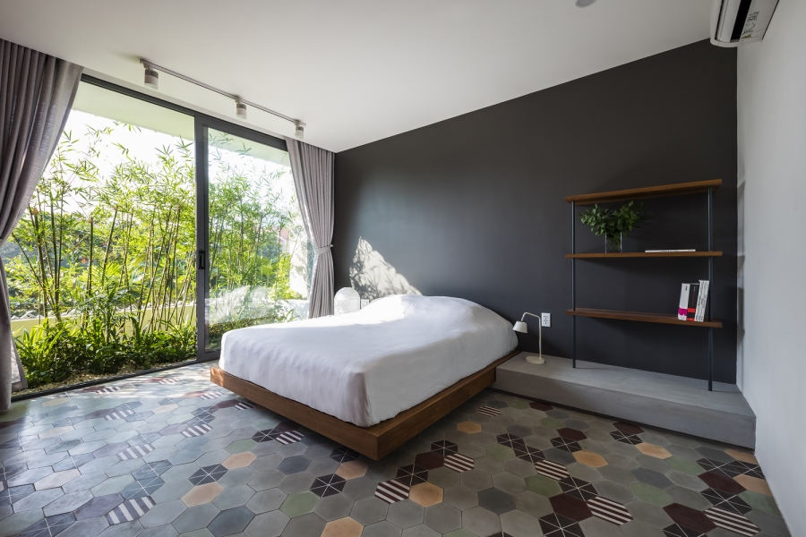 Phòng ngủ phân vùng với khu vực bên ngoài bằng cửa kính kính trượt trong suốt, view nhìn ra cây cối tươi xanh cho cảm giác thư giãn.