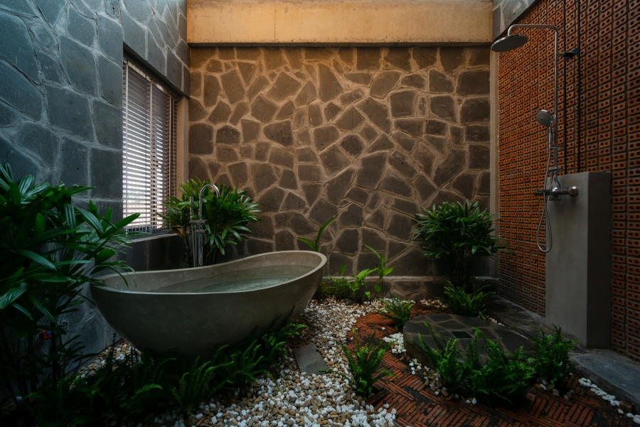 Phòng tắm kết nối với thiên nhiên nhờ gạch đất nung, đá ốp tường, những viên sỏi rải trên nền và hệ thống bồn tắm nằm, vòi tắm hoa sen ở 2 góc khác nhau.