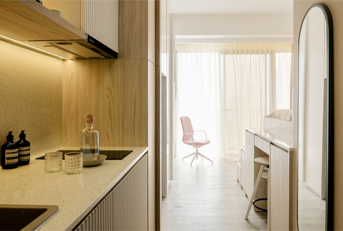 Khu vực phòng bếp thiết kế ở góc trái cánh cửa ra vào, với nội thất gọn gàng. Mặt bàn bếp và backsplash ốp gạch họa tiết Terrazzo sáng màu.