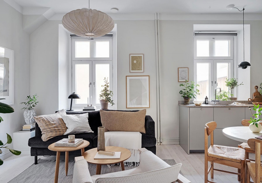 Căn hộ sử dụng gam màu xám để sơn tường và sắc trắng cho trần nhà tạo cảm giác 'nâng trần' bằng thị giác. Phòng khách với ghế sofa màu đen nổi bật, tương phản giữa những sắc màu tươi sáng.