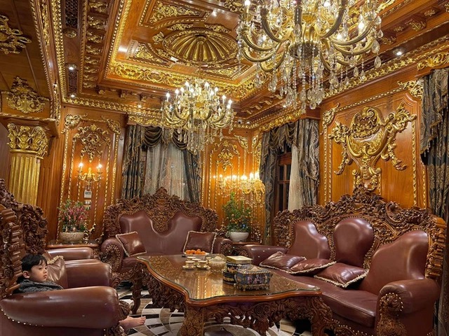 Phòng khách với những bộ sofa da sang trọng. Toàn bộ trần, tường nhà đều được chạm trổ, mạ vàng ấn tượng.