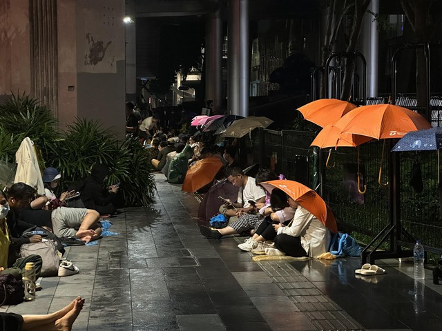 Những người đội mưa chờ mở bán iPhone tại trung tâm thương mại World Center (Thái Lan) trong đêm 21.9