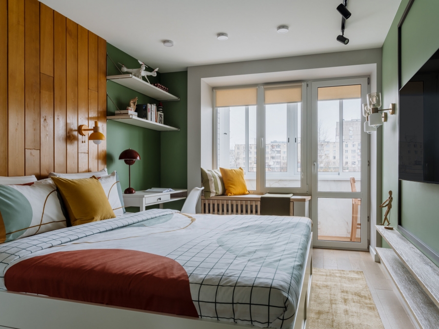 Phòng ngủ chính của bố mẹ được thiết kế với tone màu xanh lá cây chủ đạo kết hợp nội thất gỗ trang trí bức tường đầu giường, bên ngoài là logia nhỏ xinh với bộ bàn ghế nhỏ gọn.