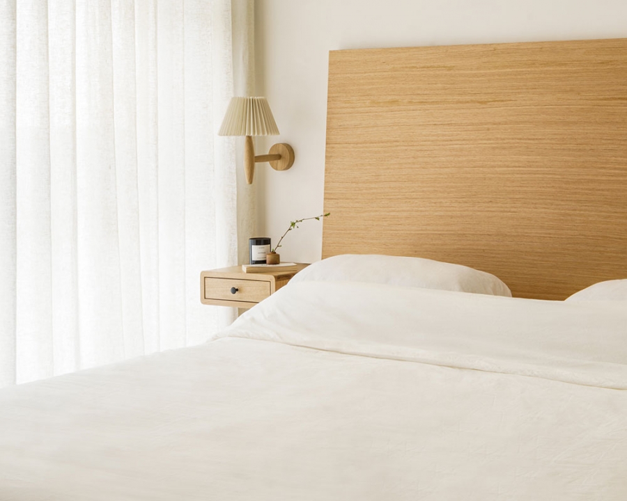 Phòng ngủ thiết kế tối giản với tone màu trắng chủ đạo, từ chăn ga gối đến rèm che mỏng nhẹ. Táp đầu giường và đèn ngủ gắn tường giúp giải phóng diện tích sàn. 