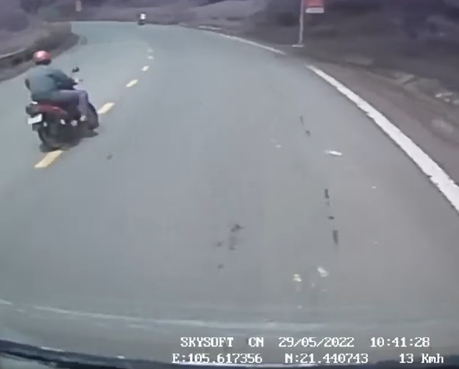 Đúng lúc tình huống đang nguy hiểm thì một người đàn ông chạy xe máy đỏ từ đằng sau đã rồ ga đuổi theo trên đoạn đường dốc