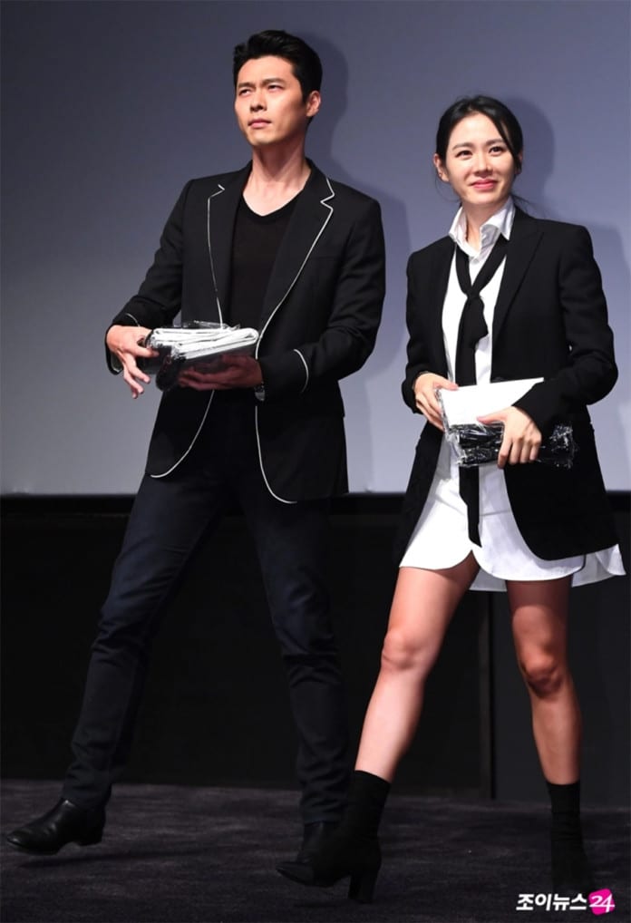 Đi cùng với Hyun Bin, theo concept đen trắng sự kết hợ của blazer đen khoác ngoài áo sơ mi giấu quần, cà vạt cách điệu và giày boot tạo ra một tổng thể thú vị cho phong cách của cô.