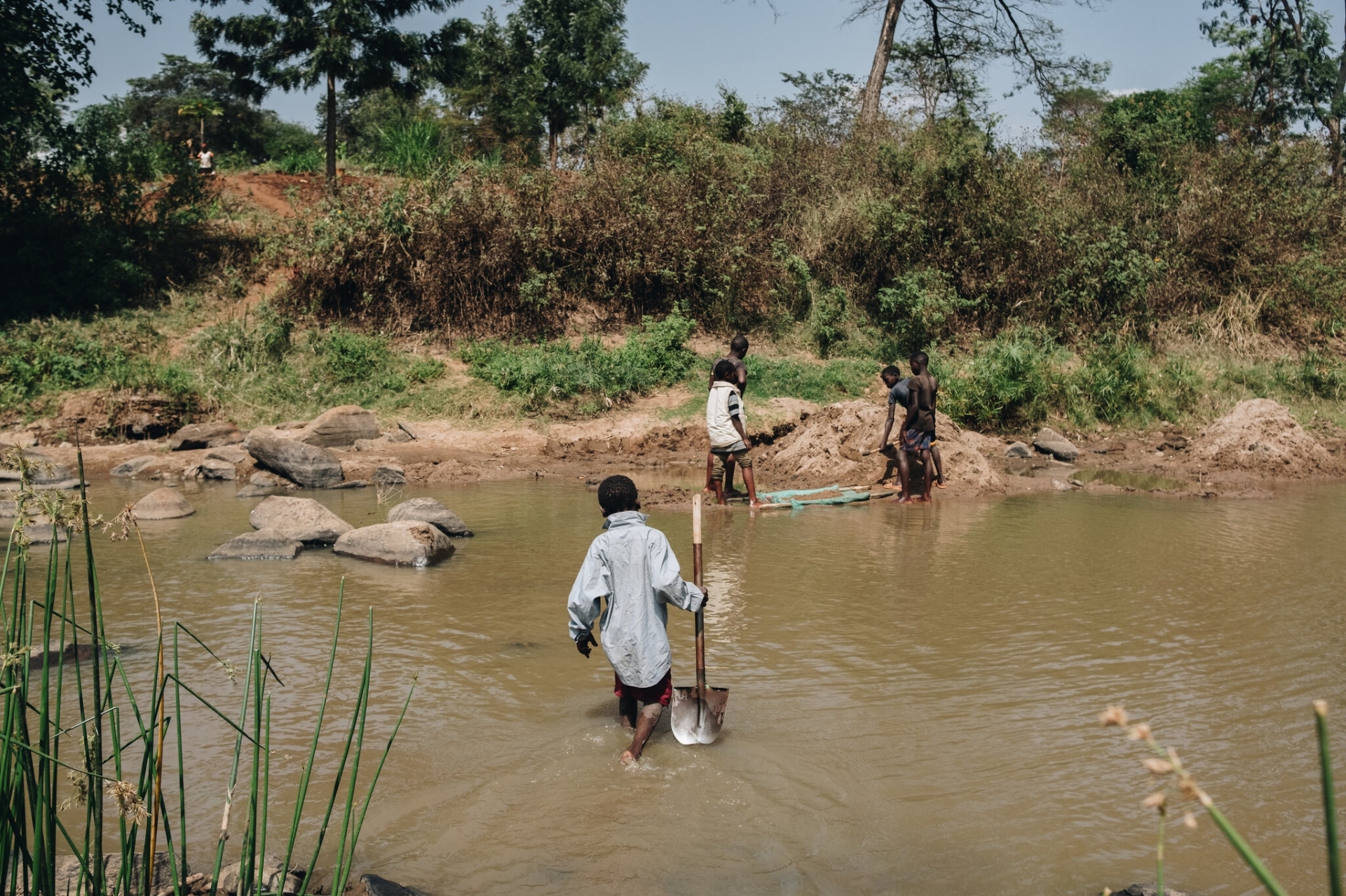 John, 10 tuổi, mang theo một cái xẻng để thu hoạch cát ở Machakos County, Kenya. John đã nuôi gia đình mình trong đại dịch Covid-19. Ảnh: The New York Times.