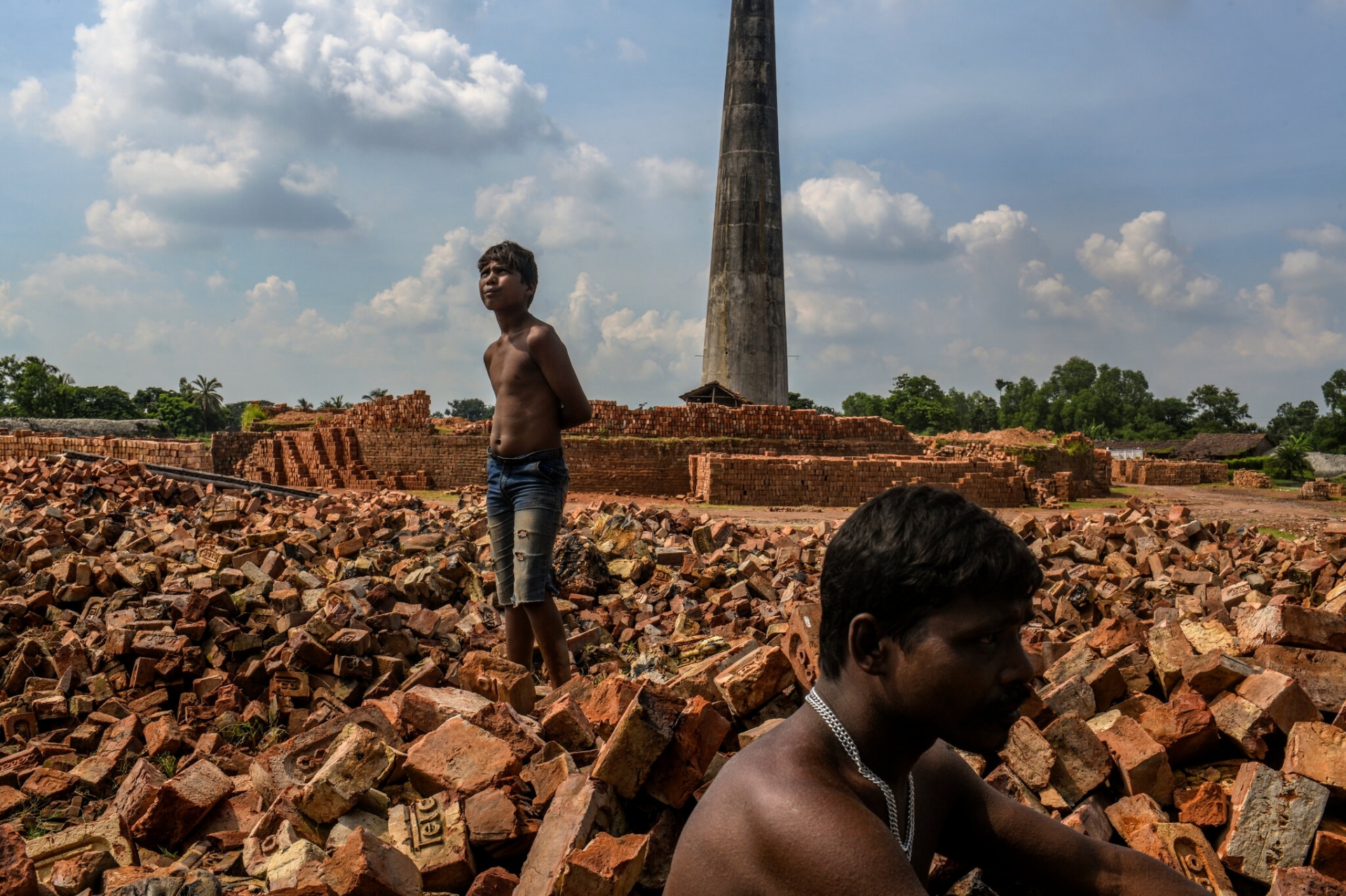 Suman Das, 13 tuổi, cùng cha đợi một chiếc xe tải đến để họ có thể chất gạch vào tháng này tại quận North Parganas của Tây Bengal (Một bang của Ấn Độ). Ảnh: The New York Times.