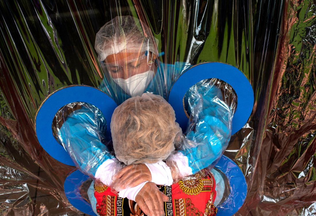 Một nhân viên y tế tuyến đầu ôm lấy dì mình trong trại dưỡng lão. Nguồn: Yuri Cortez/AFP/Getty Images.