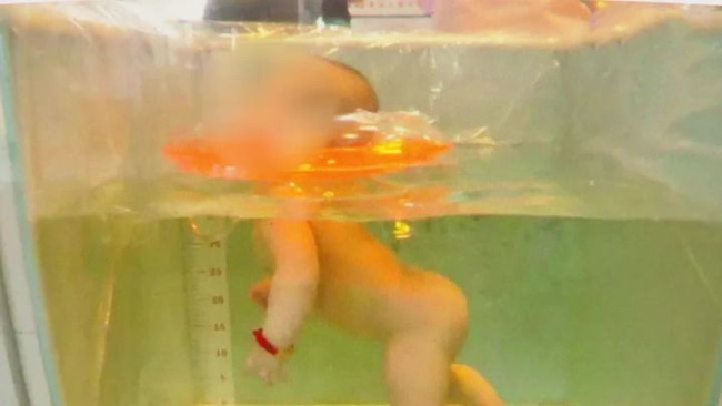 Hình ảnh Tiểu Viên dùng phao bơi giữ cổ khi bơi.