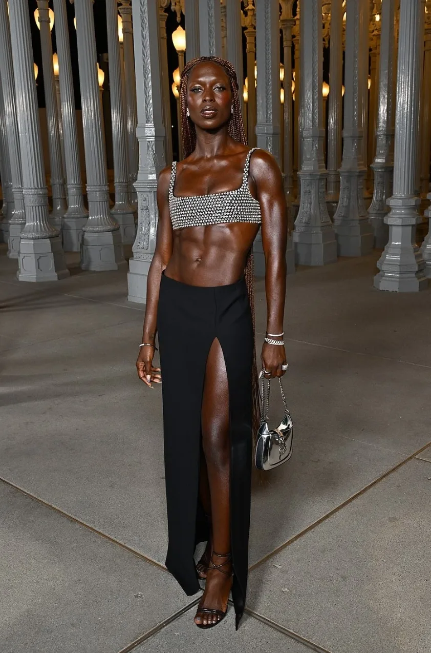 Jodie Turner-Smith khoe cơ bụng trong chiếc áo crop top màu bạc rực rỡ, kết hợp với váy maxi đen xẻ cao táo bạo.