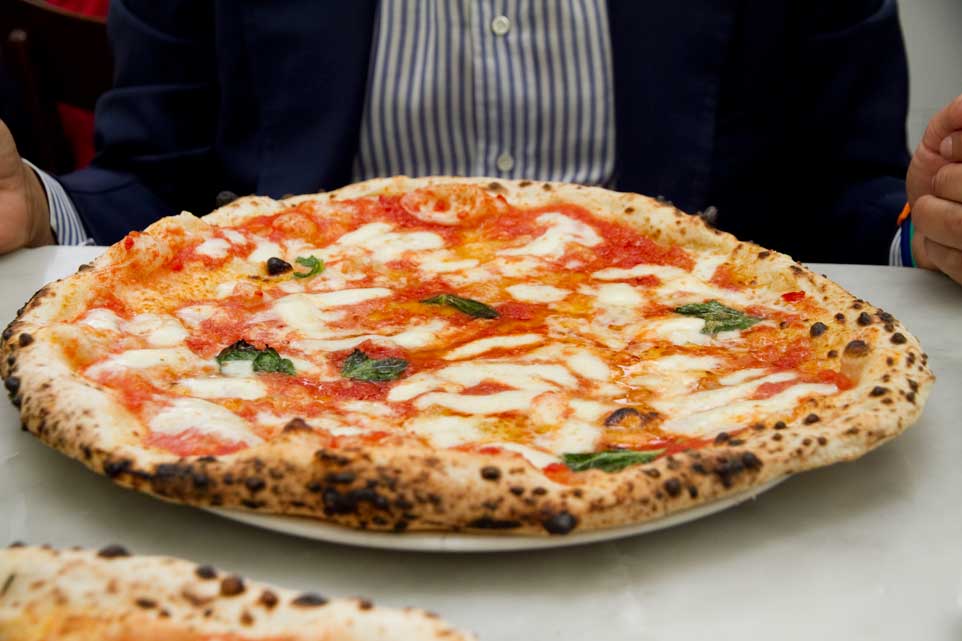 Pizza Margherita cổ điển phủ trên cùng với cà chua, phô mai fior di latte, húng quế tươi và một ít dầu đậu nành.