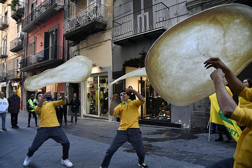 Các thành viên của Pizzaioli Acrobats Coldiretti biểu diễn bánh pizza 'xoay' để ăn mừng quyết định của UNESCO công nhận nghệ thuật 'Pizzaiuolo' của người Naples là 'di sản phi vật thể'. Ảnh: Tiziana Fabi / AFP