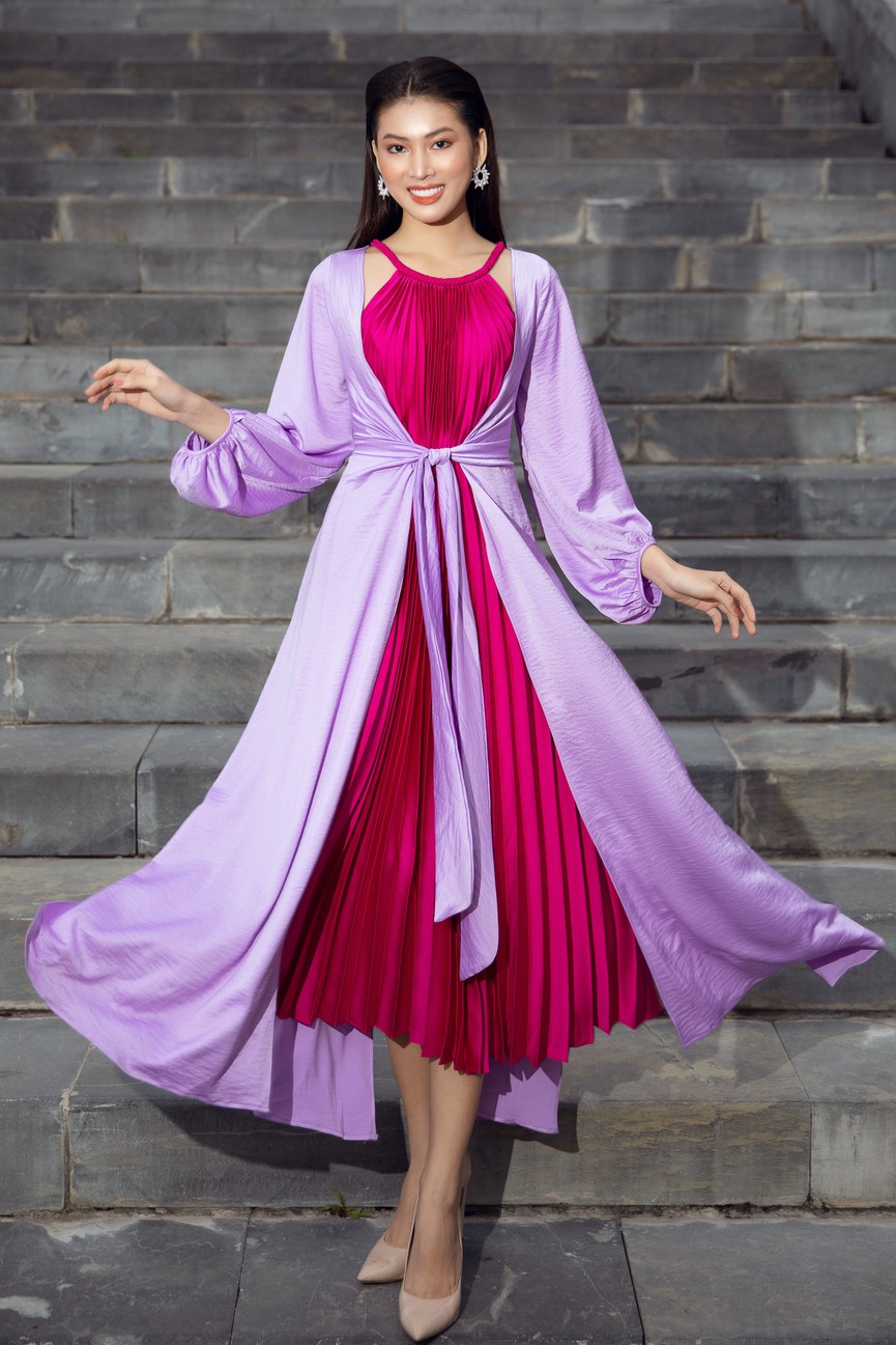 Á hậu Ngọc Thảo bay bổng với set đồ bao gồm áo choàng màu tím và váy yếm xếp ly màu hồng đậm.