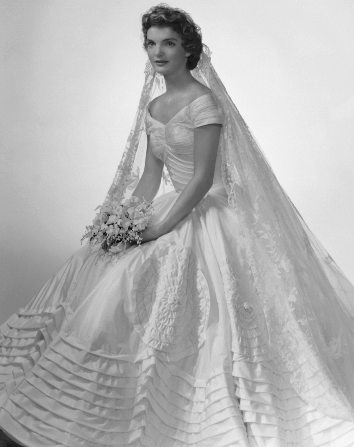 Trong hôn lễ cùng Tổng thống John F. Kennedy năm 1953, thiết kế đầm lụa màu ngà với phần eo ôm gọn thân hình mảnh mai và những tầng hoa văn in nổi mang đến vẻ thanh lịch cho nàng dâu mới. (Ảnh: Racked)