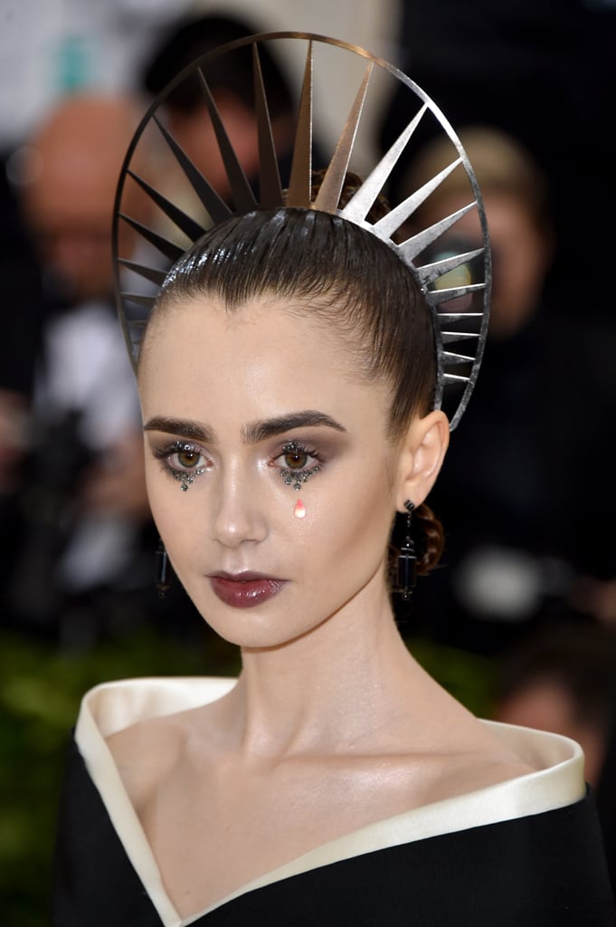 Xuất hiện tại Met Gala 2018, Lily Collins ngay lập tức choán hết mặt báo nhờ tạo hình theo phong cách Gothic ấn tượng: Đôi lông mày rậm kết hợp với cặp mắt đính đá và đôi môi ướt át.