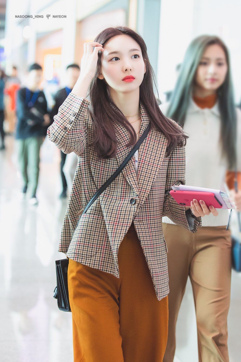 Nayeon lựa chọn cách phối màu lạ mắt hơn với áo phông trắng cùng quần màu cam sáng. Để cân bằng màu sắc, nữ idol chọn đeo một chiếc túi màu đen đơn giản.