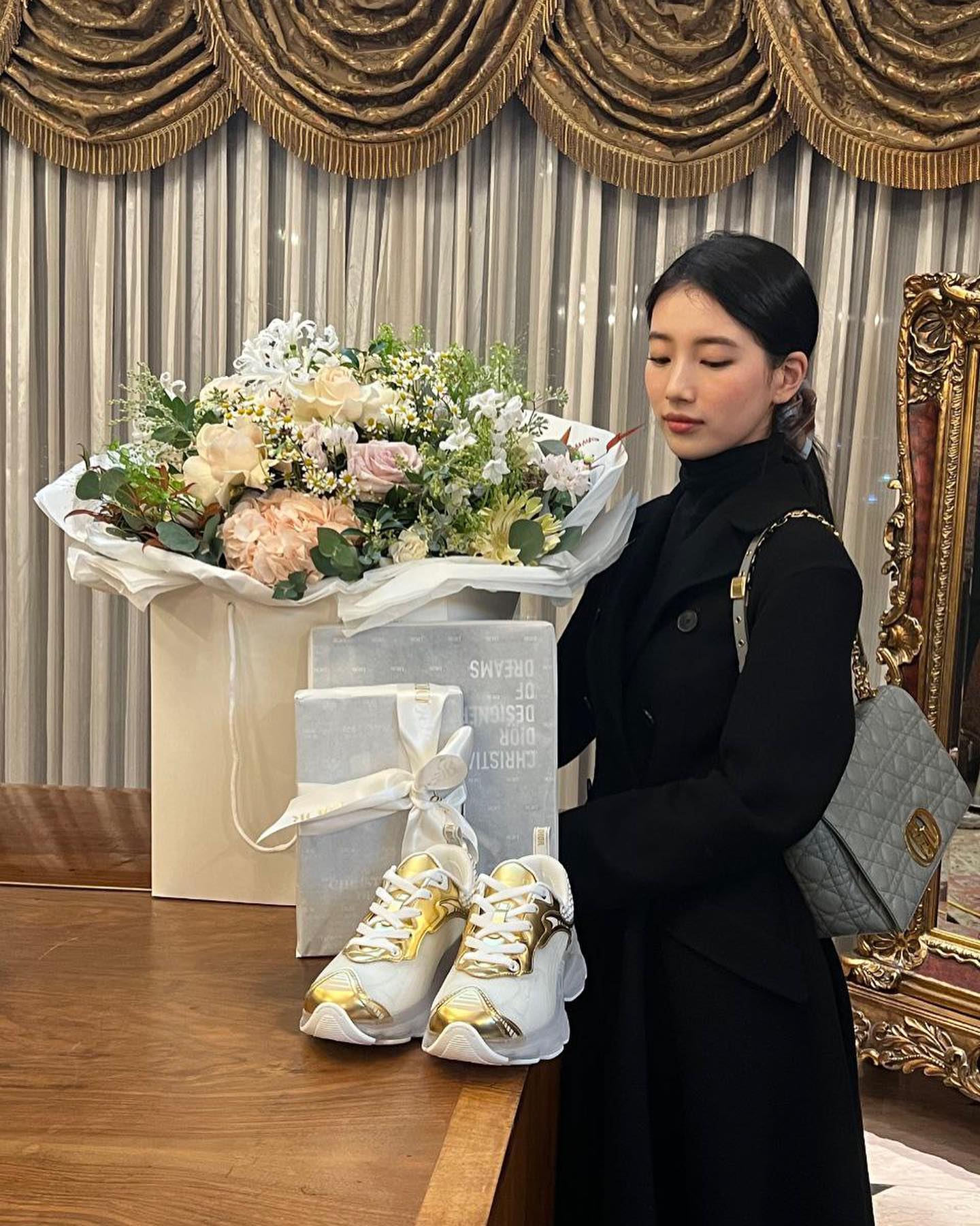 Cô nàng ăn diện cây đen tối giản để tôn lên điểm nhấn là chiếc túi Dior màu xanh pastel và đôi giày sneaker được thương hiệu gửi tặng.