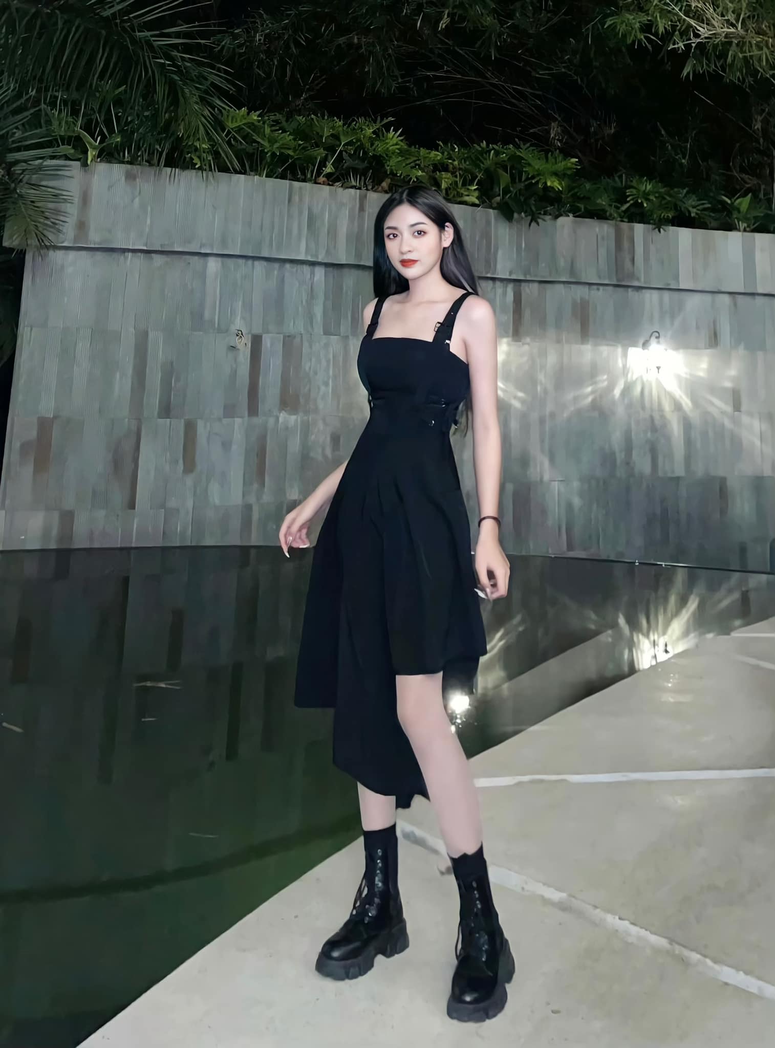 Chiếc váy đen 2 dây với thiết kế bất đối xứng đầy cá tính mix cùng đôi boots lửng hầm hố giúp hot tiktoker vừa lạ mắt, vừa ngọt ngào.