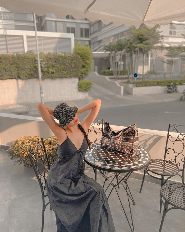 Chiếc váy xẻ ngực xâu với dáng maxi dài được Lan Khuê khéo léo mix cùng mũ bucket của Dior + túi xách Dior dáng Tote cùng màu. Dưới ánh nắng Sài Gòn, một outfit màu xanh tạo cảm giác mát mẻ, dễ chịu.